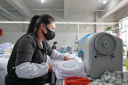 LUANNAN COUNTY, Hebei Province, China-April 8, 2020: The workers are busy on the production line in a garment factory.のeditorial素材
