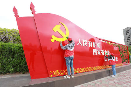LUANNAN COUNTY, Hebei Province, China-May 4, 2020: Young volunteers wipe the party flag sculpture in the park.のeditorial素材