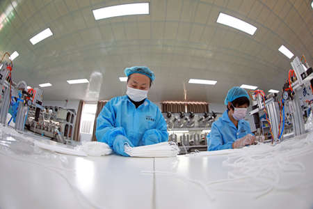 LUANNAN COUNTY, Hebei Province, China-April 15, 2020: Workers are busy on the production line in a Medical mask factory.のeditorial素材