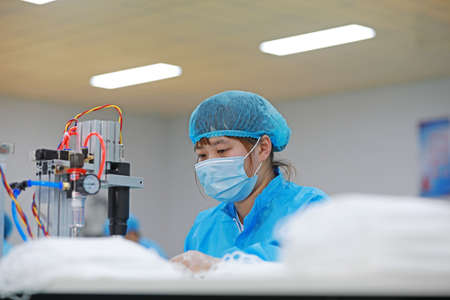 LUANNAN COUNTY, Hebei Province, China-April 15, 2020: Workers are busy on the production line in a Medical mask factory.のeditorial素材