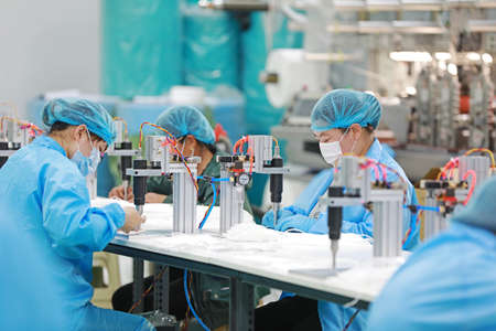 LUANNAN COUNTY, Hebei Province, China-April 15, 2020: Workers are busy on the production line in a Medical mask factory.のeditorial素材