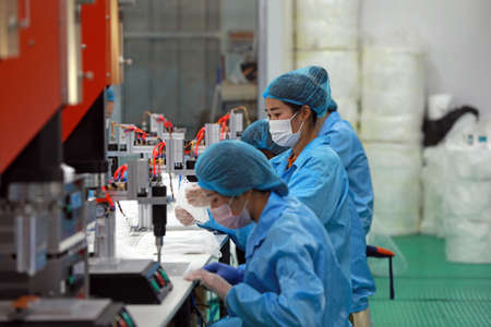 LUANNAN COUNTY, Hebei Province, China-April 23, 2020: Workers are busy on the production line in a Medical mask factory.のeditorial素材