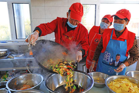 LUANNAN COUNTY, Hebei Province, China-October 16, 2020: Volunteers stir fry vegetables in the canteen for the lonely elderlyのeditorial素材