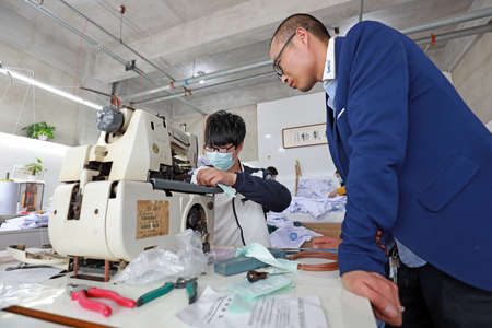 LUANNAN COUNTY, Hebei Province, China-April 8, 2020: The workers are busy on the production line in a garment factory.のeditorial素材