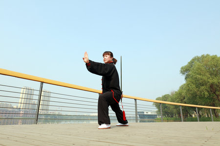 Tangshan City, Hebei Province, China - May 11, 2019: A lady in black is practicing tai chi sword in...