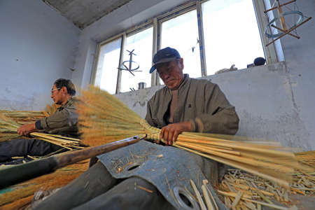 LUANNAN COUNTY, China - December 6, 2020: Workers handcraft big brooms in a workshop, LUANNAN COUNTY, Hebei Province, Chinaのeditorial素材