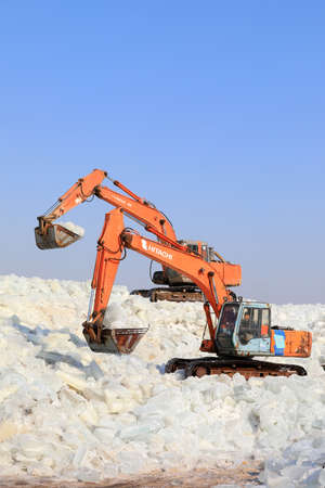 LUANNAN COUNTY, Hebei Province, China - January 14, 2020: Farmers use excavators to pack ice in a...
