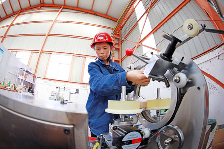 LUANNAN COUNTY, Hebei Province, China - April 15, 2019: Female workers in the operation of CNC winding machine in the workshop.のeditorial素材