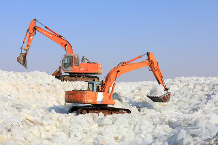LUANNAN COUNTY, Hebei Province, China - January 14, 2020: Farmers use excavators to pack ice in a storage site.のeditorial素材
