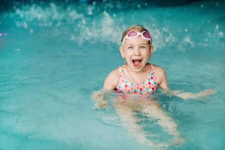 Kids play in aqua park. Children at water playground of tropical amusement park. Little girl at swimming pool. Child playing at water. Swim wear for young kid.の写真素材