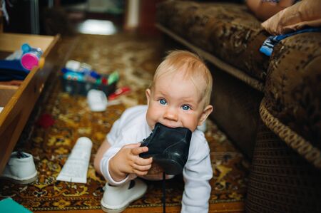 Infant Baby Child Boy Six Months Old is Takes his Shoe in the Mouth.の写真素材