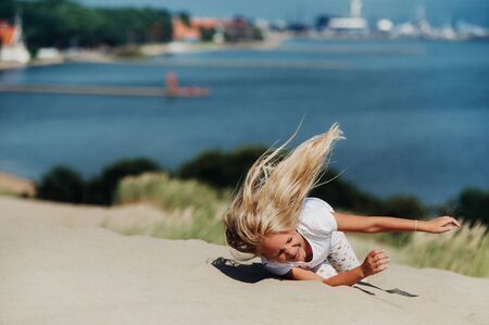 child having fun in the sand dunes on the beachの写真素材