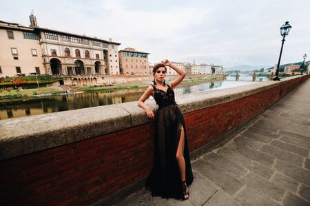 A beautiful stylish bride in a black dress walks through Florence, a Model in a black dress in the old city of Italyの写真素材