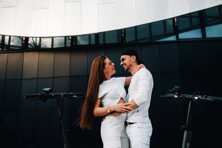 A girl and a guy are walking on electric scooters around the city, a couple in love on scooters