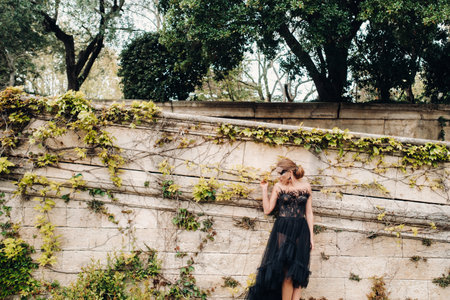 A stylish bride in a black wedding dress poses in the ancient French city of Avignon. Model in a...