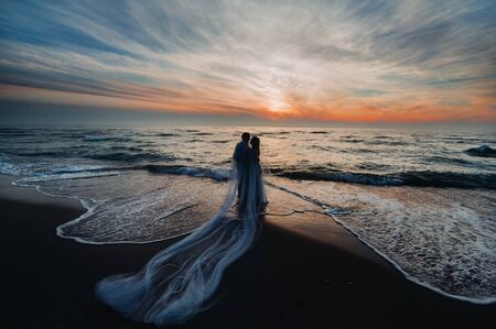 A couple in love at sunset on the background of the sea, an unrecognizable couple Portrait of a beautiful newlywed couple expecting a child. Photoの写真素材