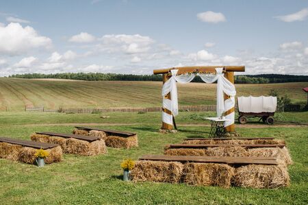 Wedding ceremony on the street in the village field.Decor with haystacks and a cart for a wedding.Rustic wedding partyの写真素材