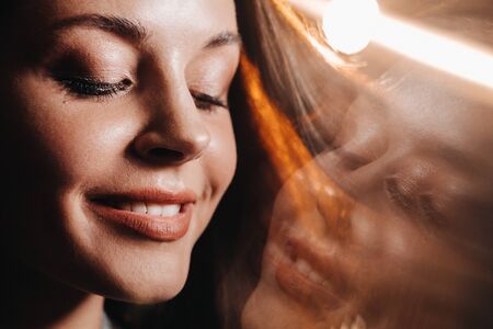 Portrait of a young European girl with long hair in a coffee shop in the evening light, a tall Girl in a jacket with long hair in a cafe.の写真素材