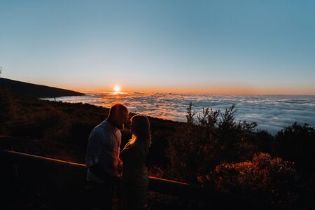 A loving man holds the girl s hand at sunset, on the background of the sea, portrait of handsome newlyweds. Photograph, conceptの写真素材