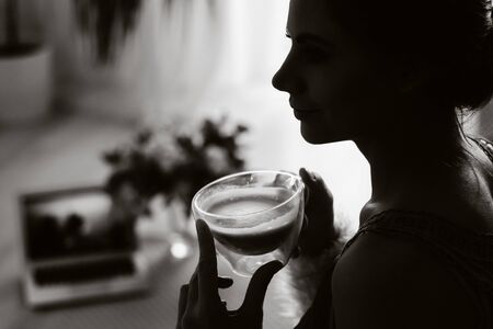 a relaxed girl at home drinks coffee and watches a movie.Domestic calm.The girl is sitting...