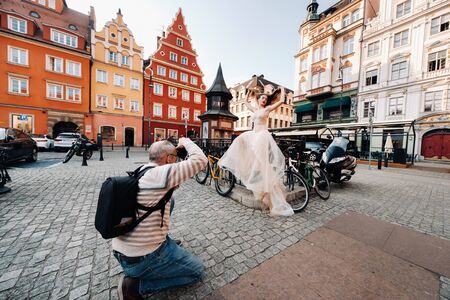 a photographer photographs a Bride in a wedding dress with long hair in the Old town of Wroclaw....
