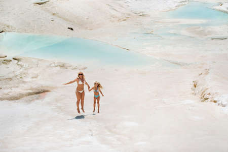 a little girl with her mother in bathing suits and sunglasses on a White mountain, a Family on a...