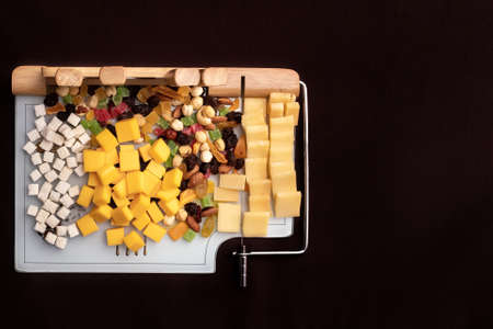 Cheese dish with various cheeses and dried fruits on a sliced Board with devices for slicing.Special Board for slicing cheese with cheese and dried fruitsの写真素材