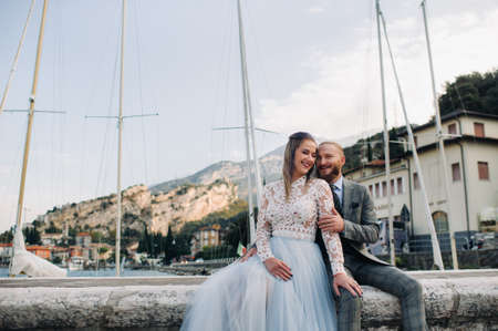Italy, Lake Garda. A beautiful couple on the shores of lake Garda in Italy at the foot of the Alps.A man and a woman sit on a pier in Italy.の写真素材