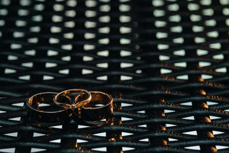 Two wedding rings and one engagement ring on a checkered grid. three gold rings of a couple in love on a gray background.Concept of love.Wedding ring.の写真素材