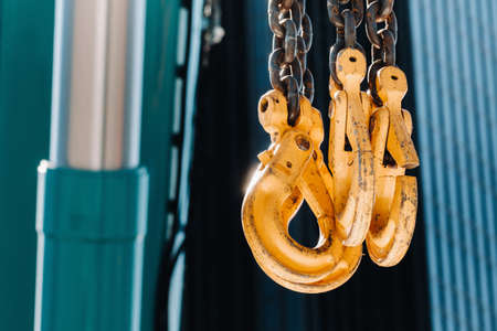 The hooks of the mobile crane near the glass of high buildings.Lots of hooks hanging from chains suspended from a craneの写真素材