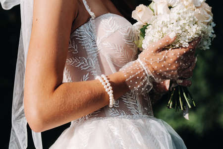 portrait of an elegant bride in a white dress with a bouquet in nature in a nature Park.Model in a wedding dress and gloves and with a bouquet .Belarusの写真素材