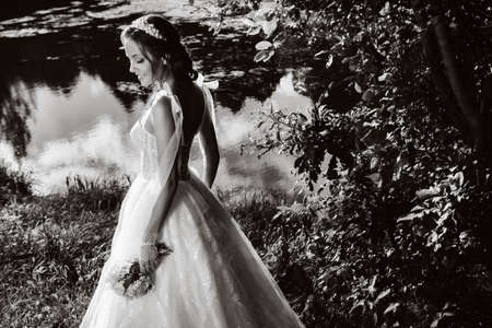 portrait of an elegant bride in a white dress with a bouquet in nature in a nature Park.Model in a wedding dress and gloves and with a bouquet .Belarusの写真素材
