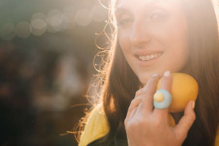 a girl in a yellow shirt with lemons in her hands on a city street. Portrait of a woman in yellow.の写真素材