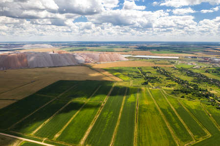Mountains of products for the production of potash salt and a green field. Salt mountains near the...