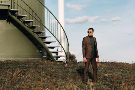 A man in a business suit and green Golf shirt stands next to a green windmill. Businessman near the windmills.Modern concept of the futureの写真素材