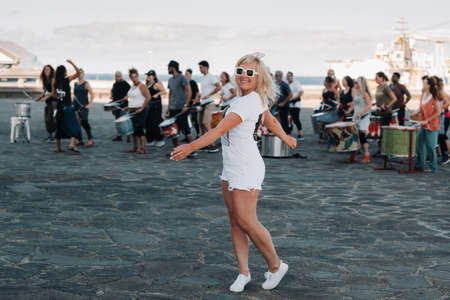 A girl in white clothes on the background of people engaged in fitness in the city of Santa Cruz de...