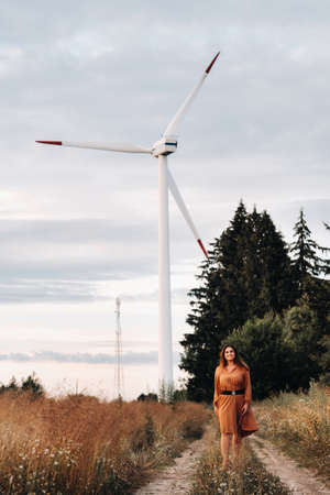 portrait of a Girl in a brown long dress with long hair in nature in the evening
