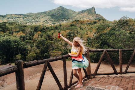 a little girl with a red can of drink in her hands against the background of the mountains of the island of Mauritius, nature reserve, Chamarel Sands.Mauritius islandの写真素材