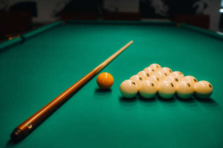 Playing pool on a green table. Balls and cue are laid out on the table.