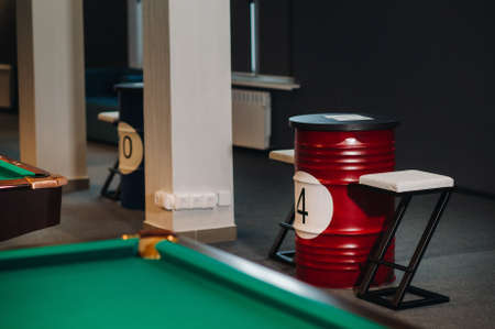 table and two chairs near the green-covered billiard table with balls in the billiard club.