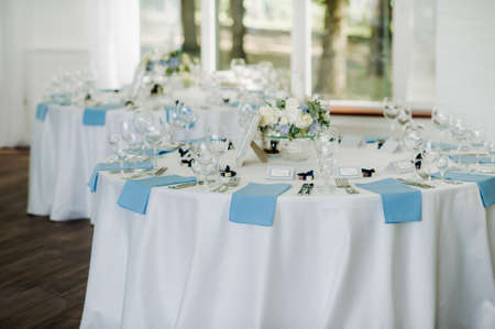 The festive table is decorated in light colors with blue napkins and flowers without food.の写真素材