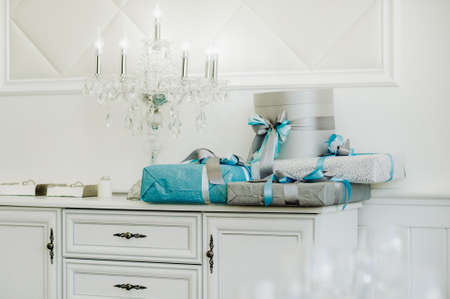 Boxes with gifts Packed in blue and silver paper are on the shelf.