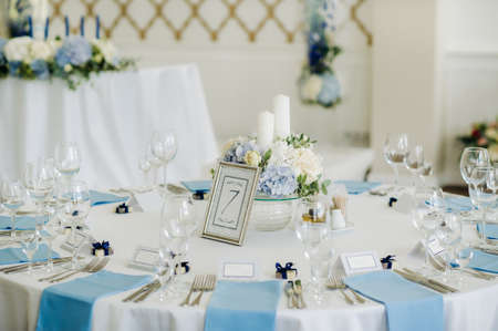 The festive table is decorated in light colors with blue napkins and flowers without food.の写真素材