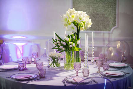 decoration of a festive dinner with flowers of lilies and tulips on the wedding table in the...