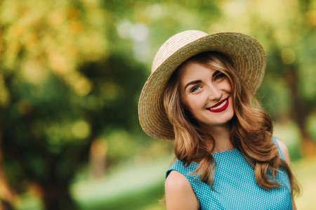portrait Of a fashionable girl in a blue dress and elegant hat in the Park.の写真素材
