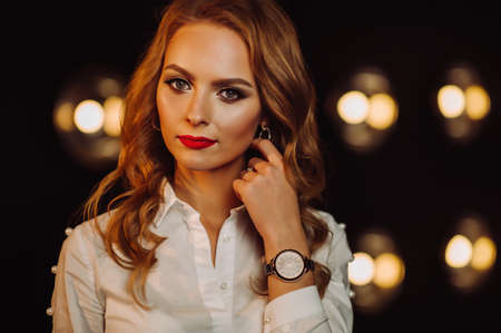 Business Woman in a white shirt against the background of burning lamps in the interior of a dark...