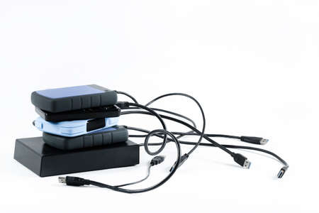 many external hard drives with wires lie on a white background. Hard drives on isolate