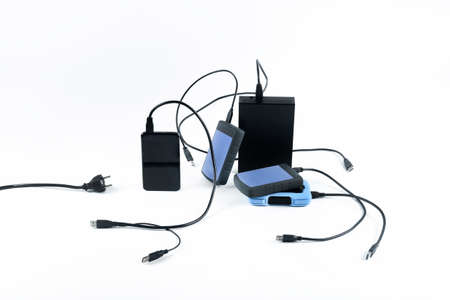 many external hard drives with wires lie on a white background. Hard drives on isolate