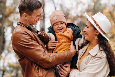 Father and mother with son walking in the autumn Park. A family walks in the Golden autumn in a nature Park.の写真素材