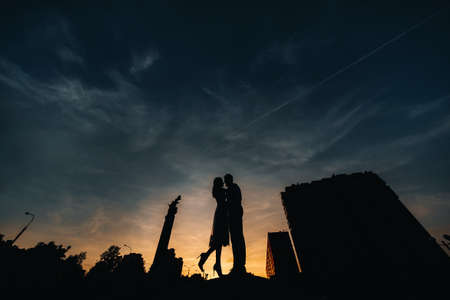 a young couple embraces in the city at a beautiful sunset, urban styleの写真素材